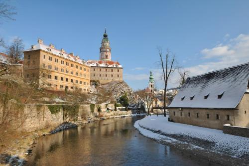 a river in front of a building with snow on the ground at Hotel Leonardo in Český Krumlov