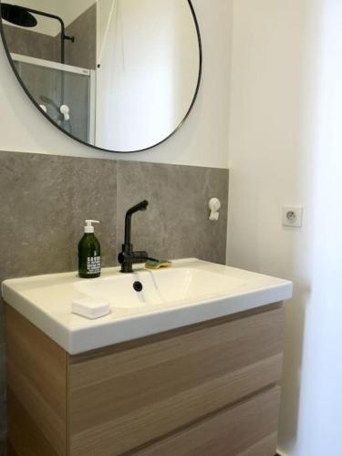 une salle de bain avec un lavabo blanc et un miroir dans l'établissement Petit Vinaigriers République CityCosy, à Paris