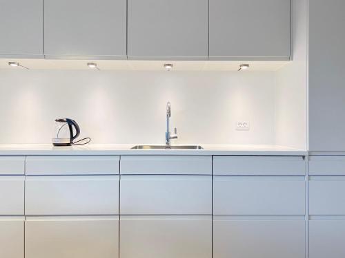 a kitchen with white cabinets and a sink at Bright And Spacious 3 Bedroom Apt In Orestaden in Copenhagen