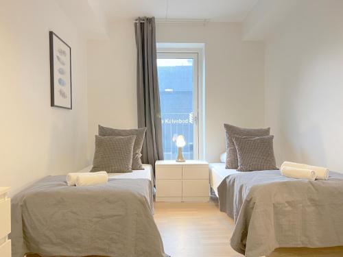 two beds in a room with a window at Bright And Spacious 3 Bedroom Apt In Orestaden in Copenhagen