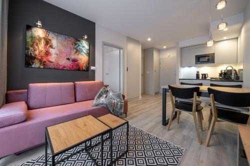 a living room with a purple couch and a kitchen at RentPlanet - Apartamenty Zakopiańskie in Zakopane