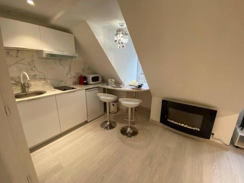 a kitchen with white cabinets and a fireplace with stools at Esprit Romantique in Mulhouse