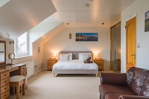 a bedroom with a white bed and a couch at Shalom - holiday home with panoramic views of the sea in Kingsdown