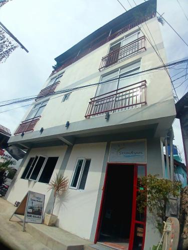 a large white building with a red door at Strandhaus Condotel in Moalboal