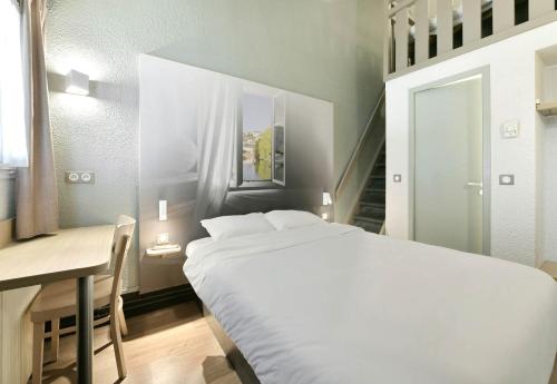 a bedroom with a bed and a table and a desk at B&B HOTEL Le Mans Sud in Arnage