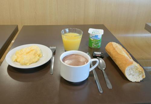 a table with a cup of coffee and a plate of food at B&B HOTEL Le Mans Sud in Arnage