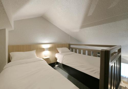 two twin beds in a room with a attic at B&B HOTEL Le Mans Sud in Arnage