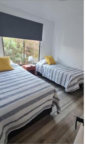 two beds in a room with a window at Casa mediterránea Villamar Guanaqueros in Guanaqueros