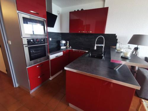 kuchnia z czerwonymi szafkami i czarnym blatem w obiekcie 176 Indes Galantes G91 w Cap d'Agde