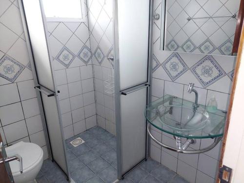 La salle de bains est pourvue d'un lavabo en verre et de toilettes. dans l'établissement Cobertura com terraço e churrasqueira, à Florianópolis