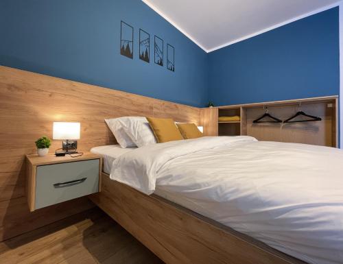 a bedroom with a large white bed with blue walls at 1320 Apartments in Sibiu
