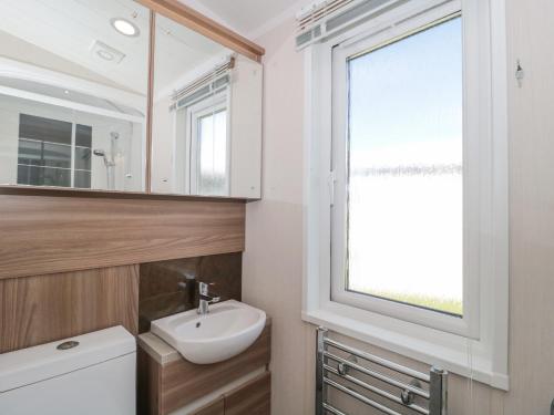 baño con aseo y lavabo y ventana en The Olive Lodge, 227 Sycamore, en New Milton