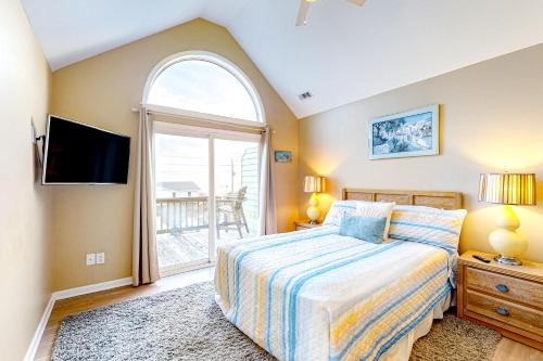 1 dormitorio con cama y ventana grande en Dog Daze of Summer East en Emerald Isle