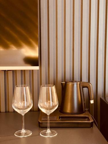 two wine glasses sitting on a table with a tea kettle at Tirana Central Rooms in Tirana