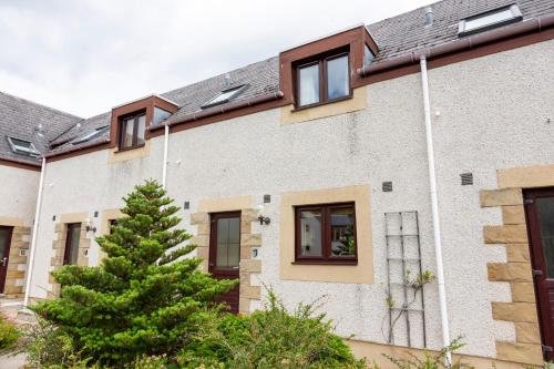 a house with a tree in front of it at Scandinavian Village Ltd in Aviemore