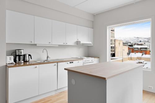 kuchnia z białymi szafkami i dużym oknem w obiekcie Downtown Apartment - THE VIEW w mieście Tromsø