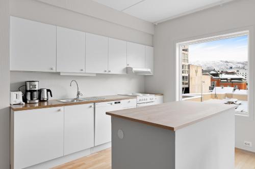 a kitchen with white cabinets and a large window at Downtown Apartment - THE VIEW in Tromsø