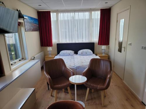 a bedroom with a bed and two chairs and a table at pension canberra in Bergen aan Zee