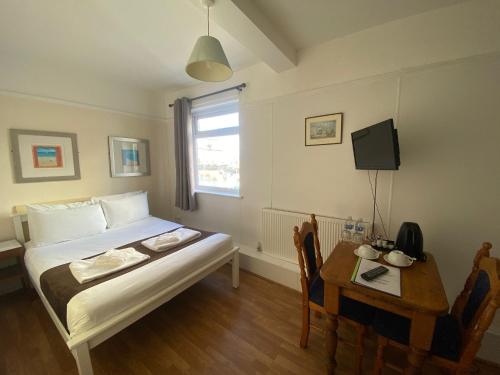 ポーツマスにあるLady Hamilton Public House B&Bのベッド1台、テーブル、電話が備わる小さな客室です。