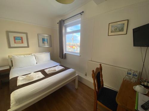 a small bedroom with a bed and a window at Lady Hamilton Public House B&B in Portsmouth