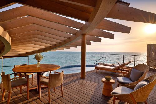 a deck with a table and chairs and the ocean at The St. Regis Red Sea Resort in Ḩanak