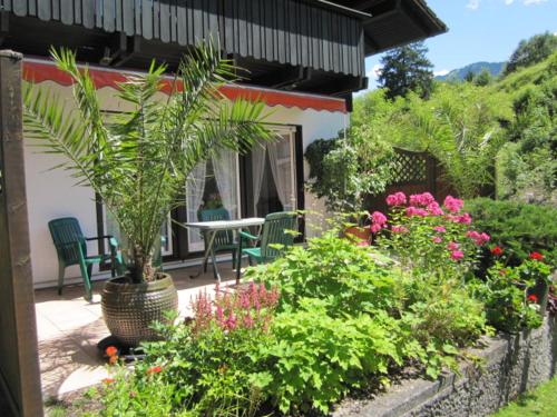 einen Garten mit einem Tisch, Stühlen und Blumen in der Unterkunft Komfort-Ferienhaus Alpspitz in Grainau