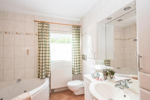 a bathroom with a tub and a toilet and a sink at Komfort-Ferienhaus Alpspitz in Grainau