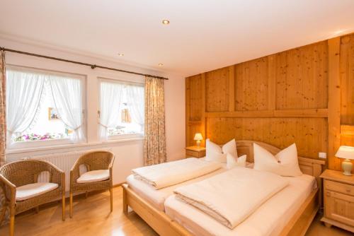 a bedroom with a large bed and two windows at Komfort-Ferienhaus Alpspitz in Grainau