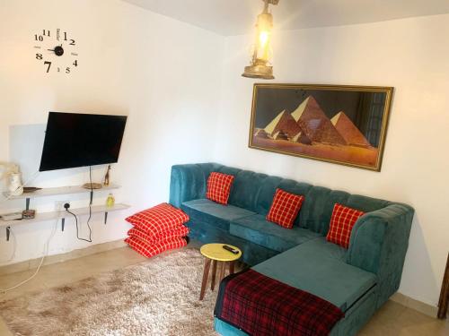 a living room with a blue couch and a tv at Rorot Spacious one bedroom in Kapsoya with free Wifi in Eldoret