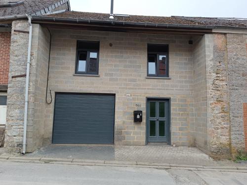 - un bâtiment en briques avec deux portes de garage et deux fenêtres dans l'établissement Le cocon, à Gochenée