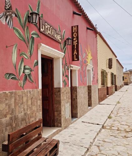 ein rotes Gebäude mit einer Bank davor in der Unterkunft La Puerta Verde in Humahuaca
