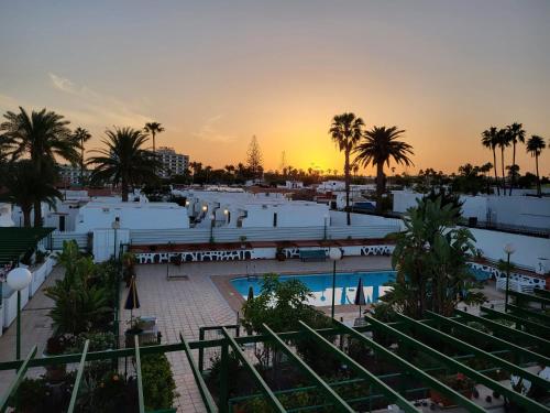 ein Resort mit Pool, Palmen und Sonnenuntergang in der Unterkunft Felicidad in Playa del Ingles