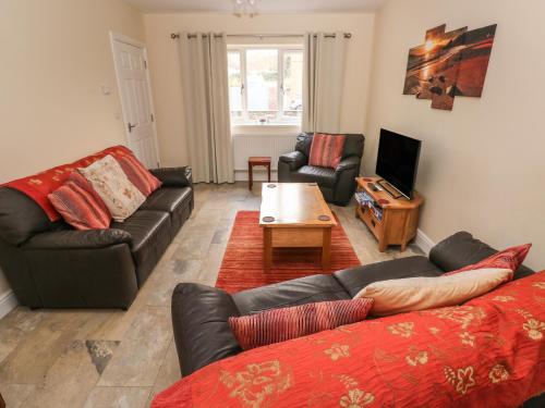 a living room with two couches and a table at Llygad Yr Haul Sun in Burry Port
