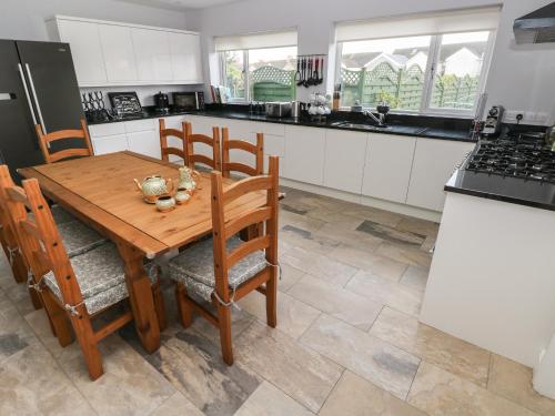 a kitchen with a wooden table and chairs and a refrigerator at Llygad Yr Haul Sun in Burry Port