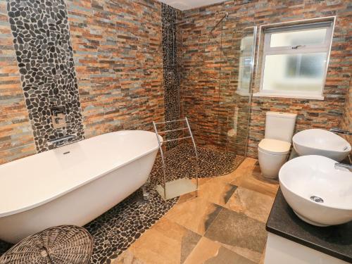 a bathroom with a white bath tub and a toilet at Llygad Y Lleuad Moon in Burry Port