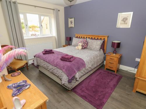 ein Schlafzimmer mit einem Bett mit einer lila Decke in der Unterkunft Llygad Y Lleuad Moon in Burry Port