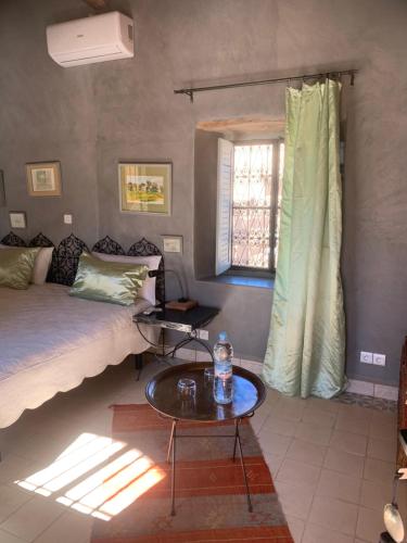 a bedroom with a bed and a table and a window at RIAD CHANT D'ETOILES tadighoust in El Hara