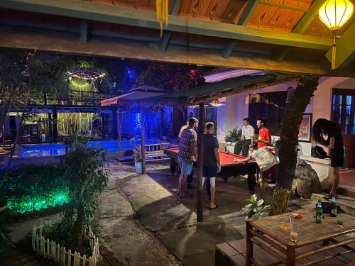 a group of people standing around a pool table at Heliport Hostel in Hoi An