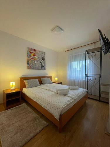 a bedroom with a bed with two lamps and a window at Kuća za odmor Saturnus in Karanac