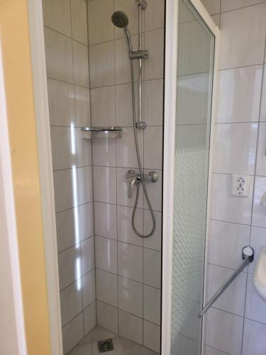 W łazience znajduje się prysznic ze szklanymi drzwiami. w obiekcie Pension Canberra w mieście Bergen aan Zee