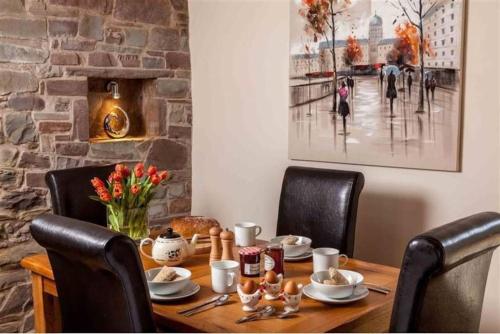 a dining room table with chairs and a painting on the wall at Trefaen Cottage in Brecon