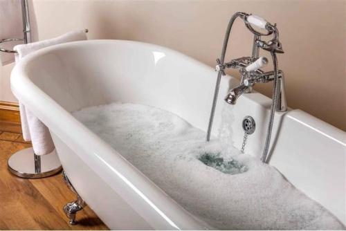 uma banheira cheia de água na casa de banho em Trefaen Cottage em Brecon