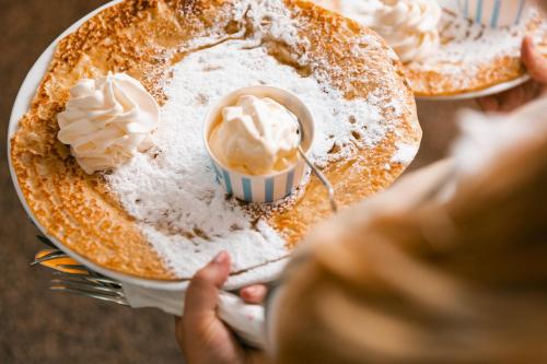 a person holding two plates of pancakes with ice cream at De Lindenhoeve Boutique Hotel in Sluis