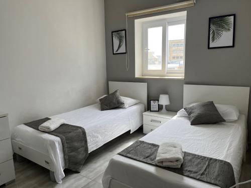 a bedroom with two beds and a window at F5 Modern and Bright Apartment in Malta in Msida