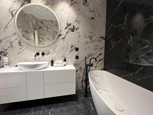 La salle de bains est pourvue d'un lavabo blanc et d'un miroir. dans l'établissement Baltic Riviera Apartments - Granaria Sauna Apartment, à Gdańsk