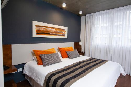 サン・ミゲル・デ・トゥクマンにあるAmérian Tucuman Apart & Suitesのベッドルーム(オレンジ色の枕が付いた大きな白いベッド付)