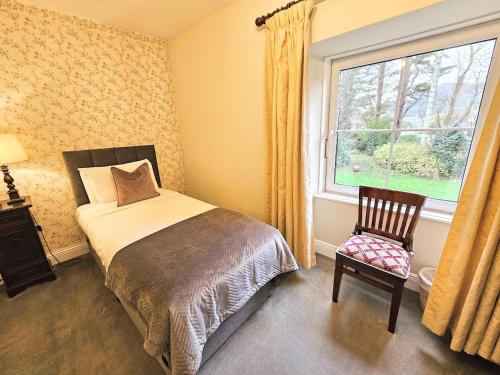 a bedroom with a bed and a window and a chair at The Glenbeigh Hotel in Glenbeigh