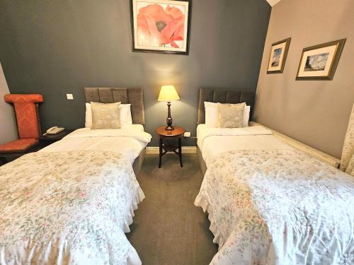 a room with two beds and a table with a lamp at The Glenbeigh Hotel in Glenbeigh