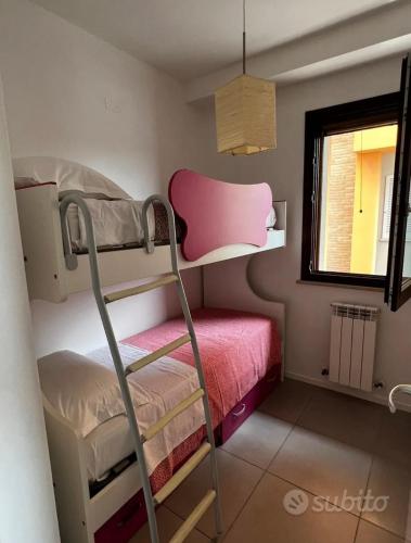 a bunk bed in a small room with a pink chair at Casa di Sveva in Marotta