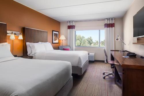 a hotel room with two beds and a desk at Four Points by Sheraton at Phoenix Mesa Gateway Airport in Mesa